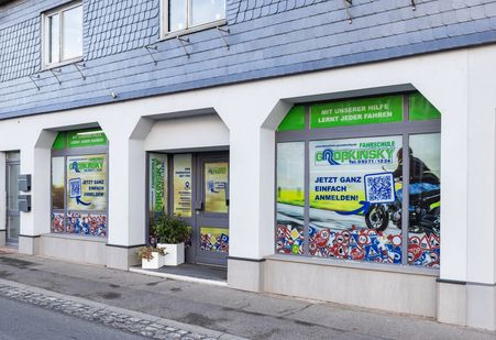 Außenansicht einer Fahrschule mit farbenfrohen Fenstergrafiken | Fahrschule Großkinsky GmbH